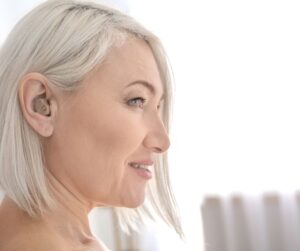 Older woman with white hair wearing hearing aid